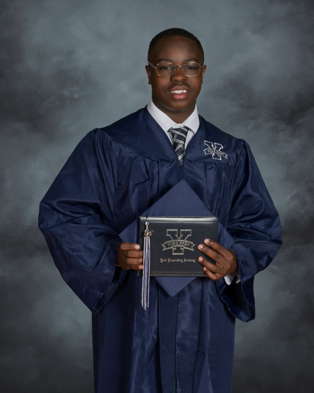 Nicholas Minott in his York Prep cap and gown, holding his diploma